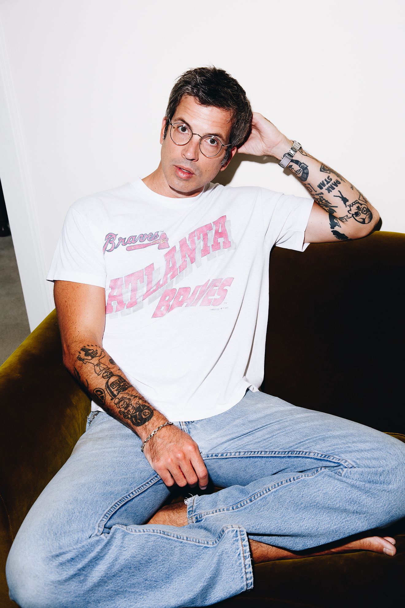 Image may contain Clothing Sleeve Person Skin Tattoo Sitting TShirt Pants Adult Arm and Body Part